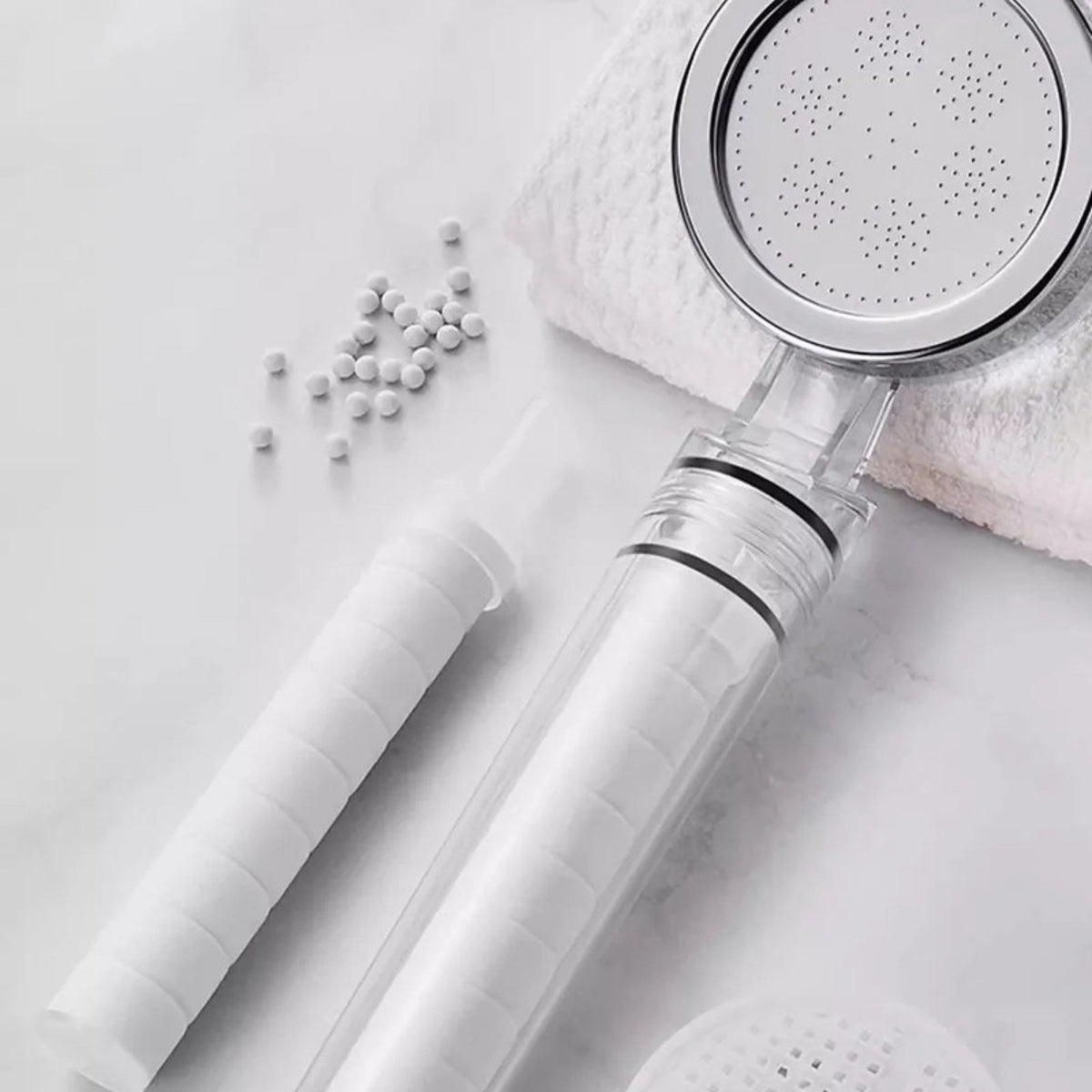 Pommeau filtrant Nevya et billes filtrantes dans une salle de bain